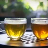 Two glass cups showing the color difference in First Flush vs Second Flush Darjeeling Tea.